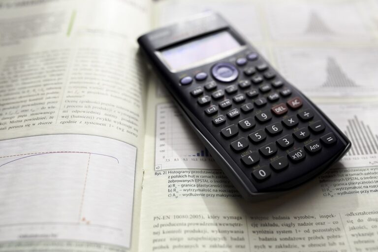 Kalkulator naukowy leżący na otwartej książce z wykresami